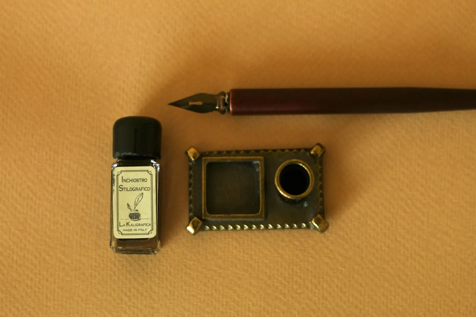 Fountain pen with ink bottle and brass inkwell on a table